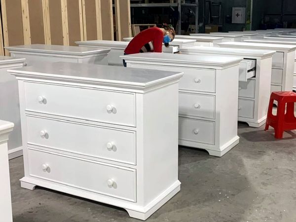 Nhân viên kiểm tra ngăn kéo của tủ phòng em bé màu trắng trước khi đóng gói